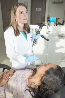 Foto de la doctora realizando una nasolaringoscopia a una paciente acostada